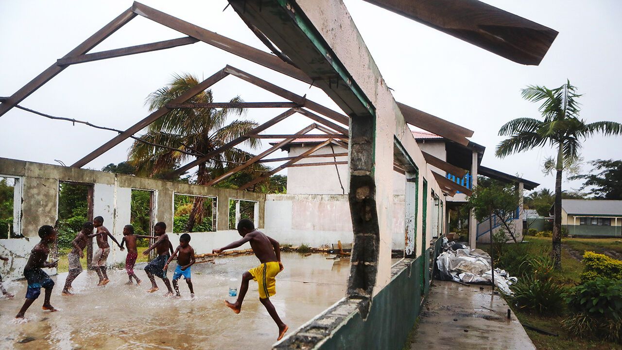Children play in the rain in a Vanuatu school building heavily damaged by Cyclone Pam