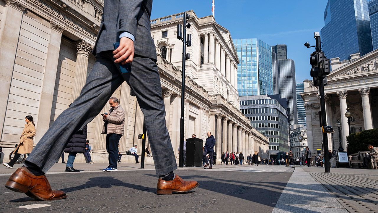A man's legs seen walking past the Bank of England in the City of London