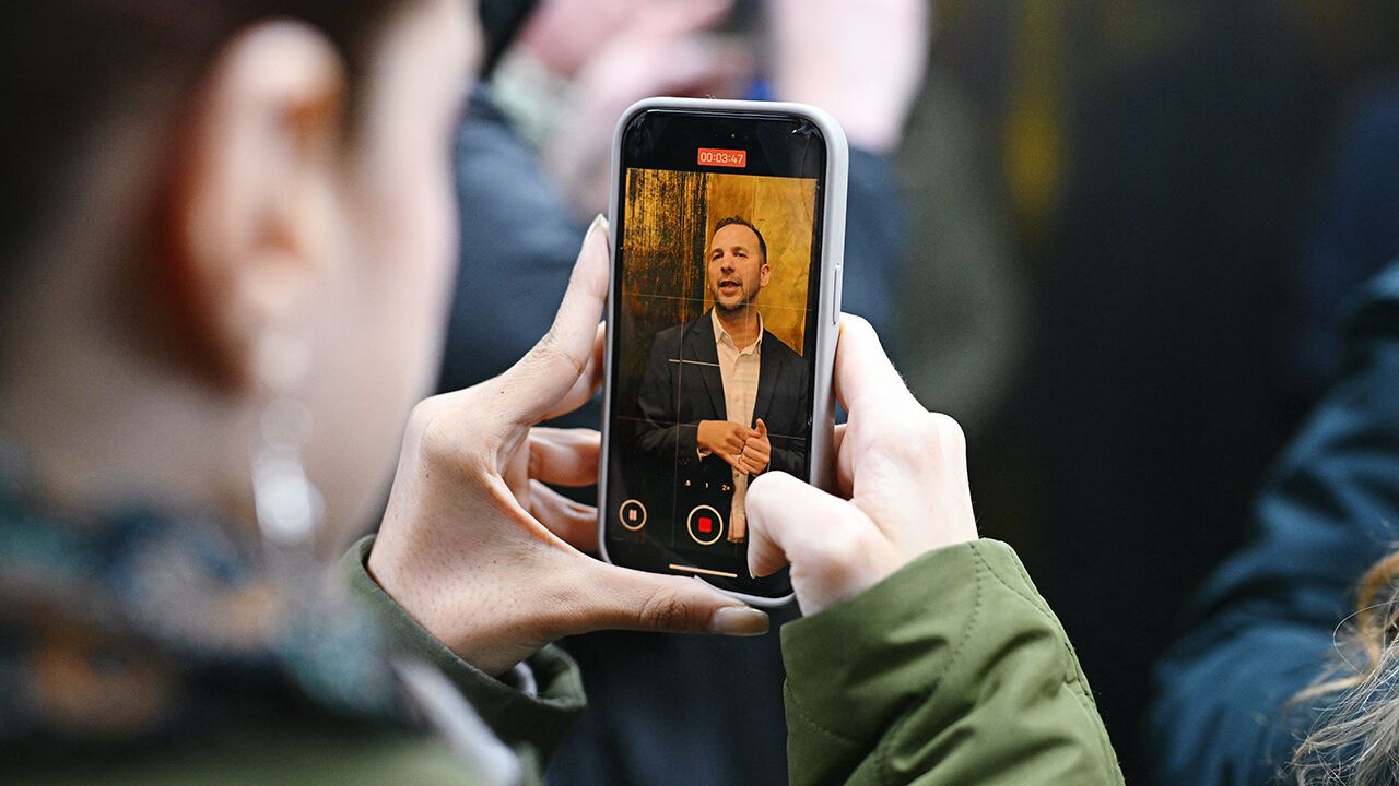 The leader of Britain's Green Party, Zack Polanski, is pictured on a phone screen