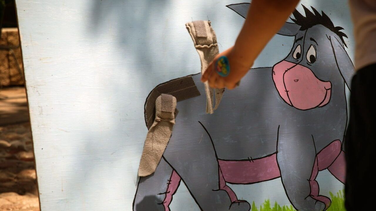A partygoer attempts to pin the tail on Eeyore at the annual birthday party.