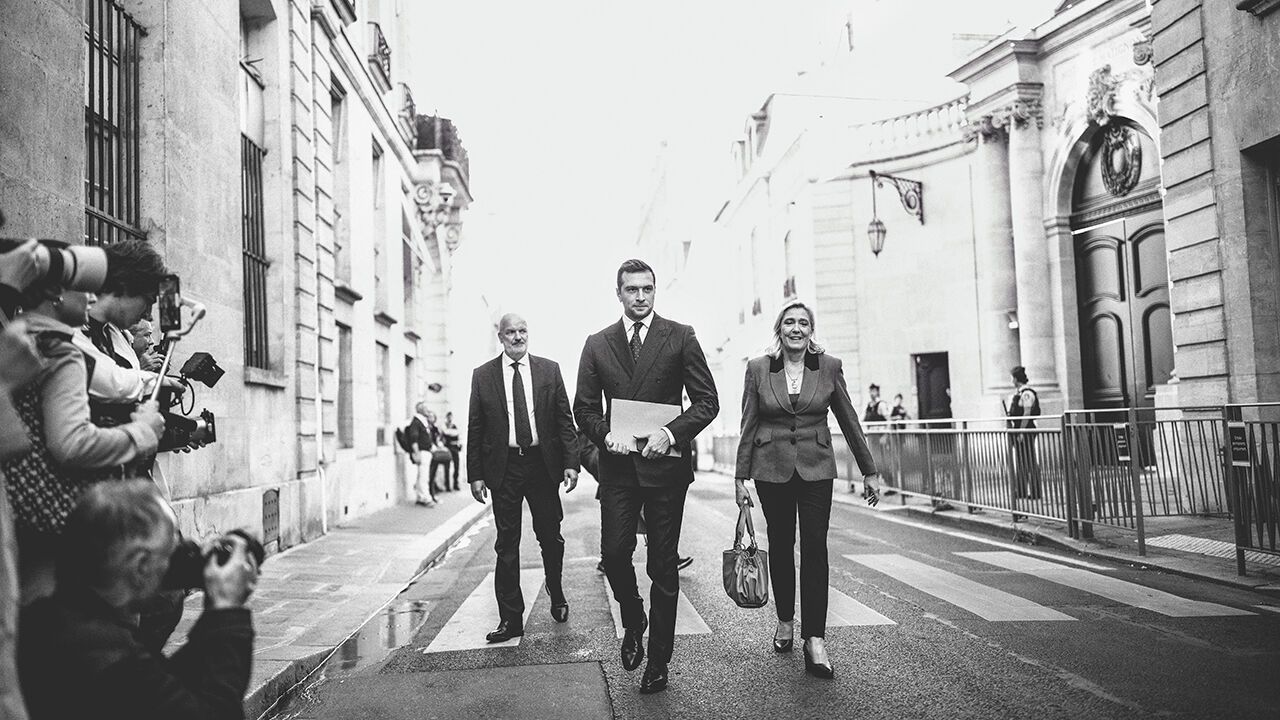 Jordan Bardella and Marine Le Pen walking towards the camera.