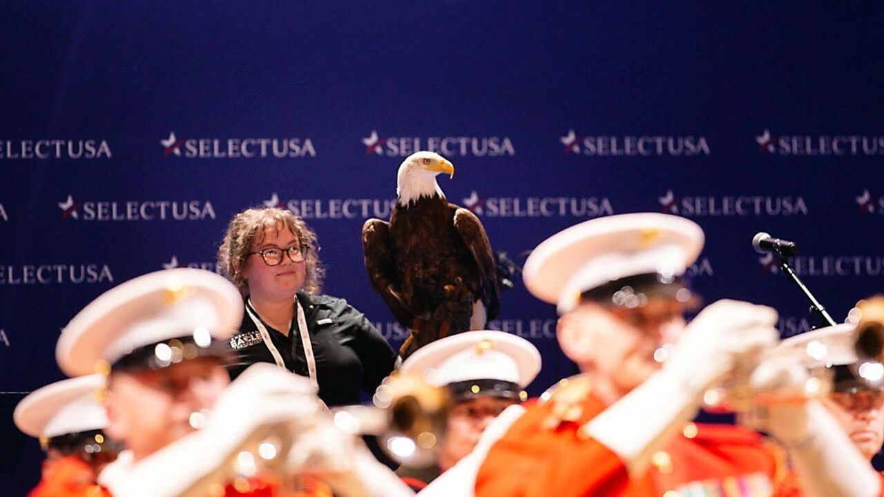 An eagle in seen behind a marching band at the SelectUSA Summit.