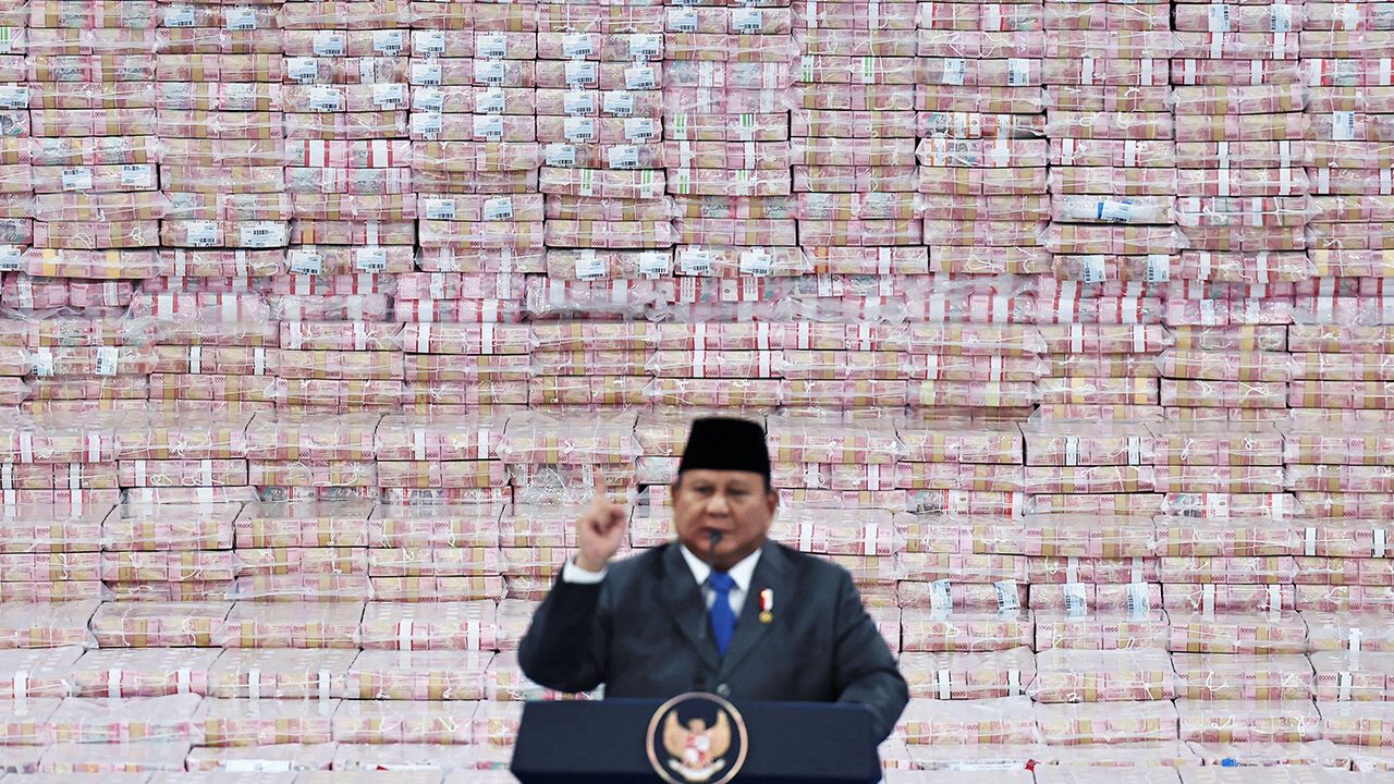 Indonesian President Prabowo Subianto makes a speech in fron the stacks of rupiah banknotes 