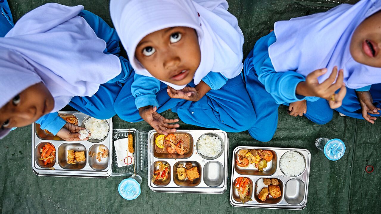 Children eat food supplied by the Indonesian government's free meal program in Banda Aceh