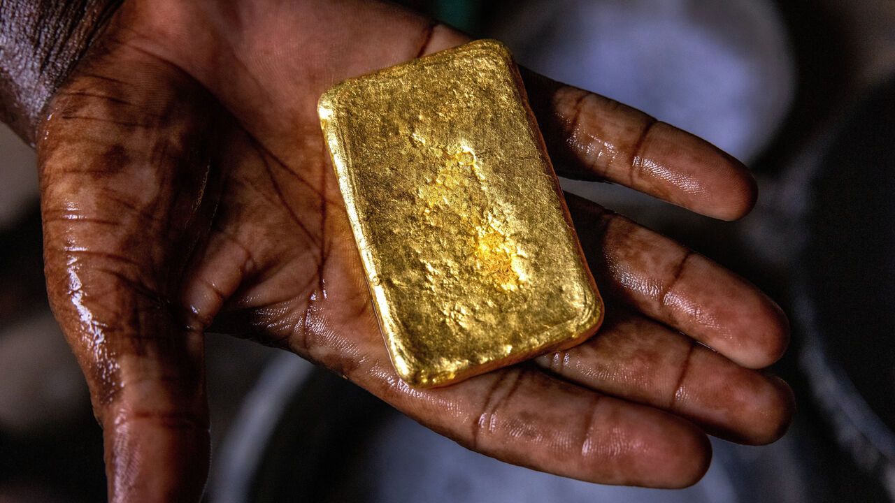 A gold trader holds an ingot in his open hand.