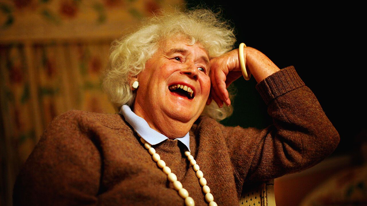 Writer Jan Morris lauughs on a sofa.