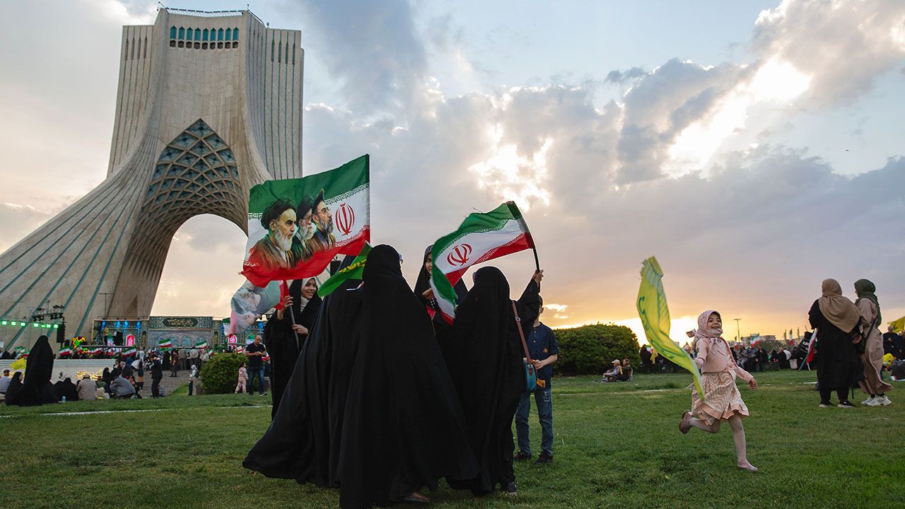 People gather in Azadi square, holding flags with faces of the three supreme leaders at a government-organized march.