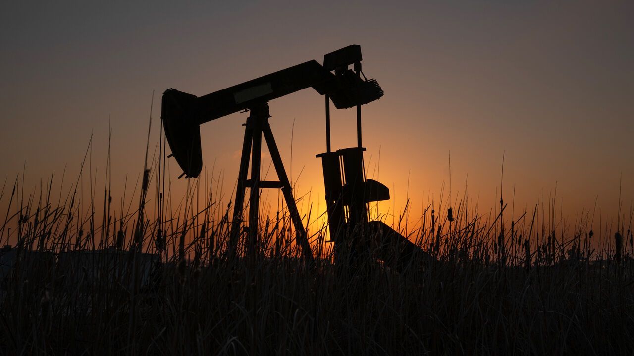 An oil pump jack with setting sun behind.
