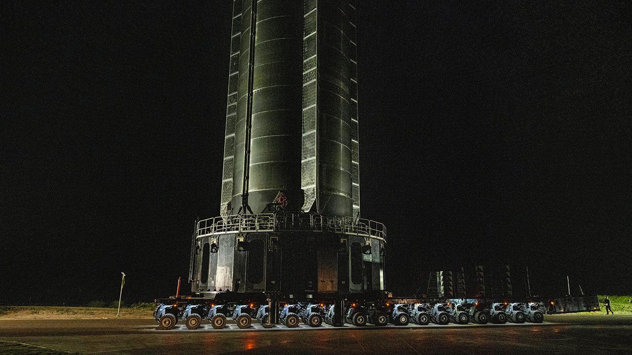 The SpaceX Super Heavy booster rolls past the production facility toward launch pad 2 ahead of the 12th test flight of the Starship spacecraft in Starbase, Texas