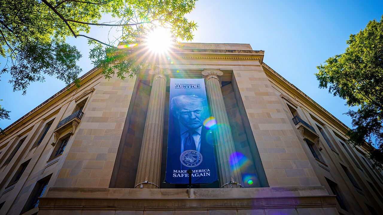 A large image of U.S. President Donald Trump hangs from the the Robert F. Kennedy Department of Justice Building.