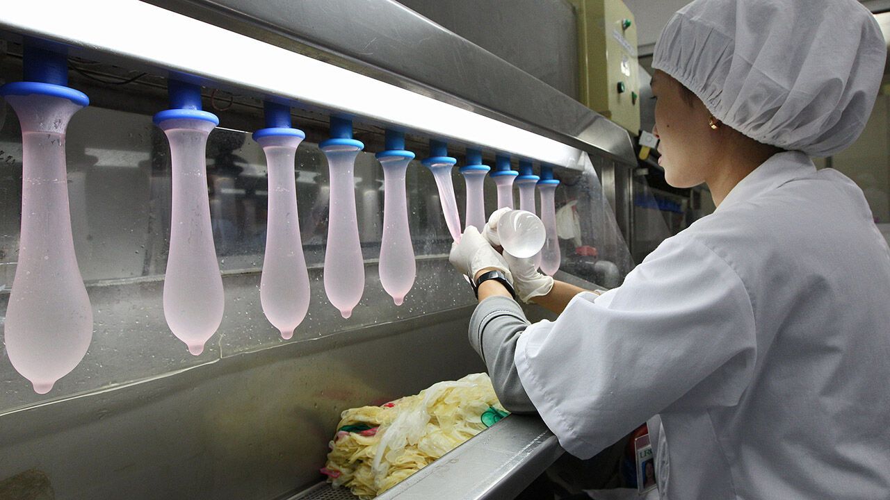 An employee inspects condoms during testing in the research laboratory at the Karex Industries condom factory in Pontian Besar, Malaysia