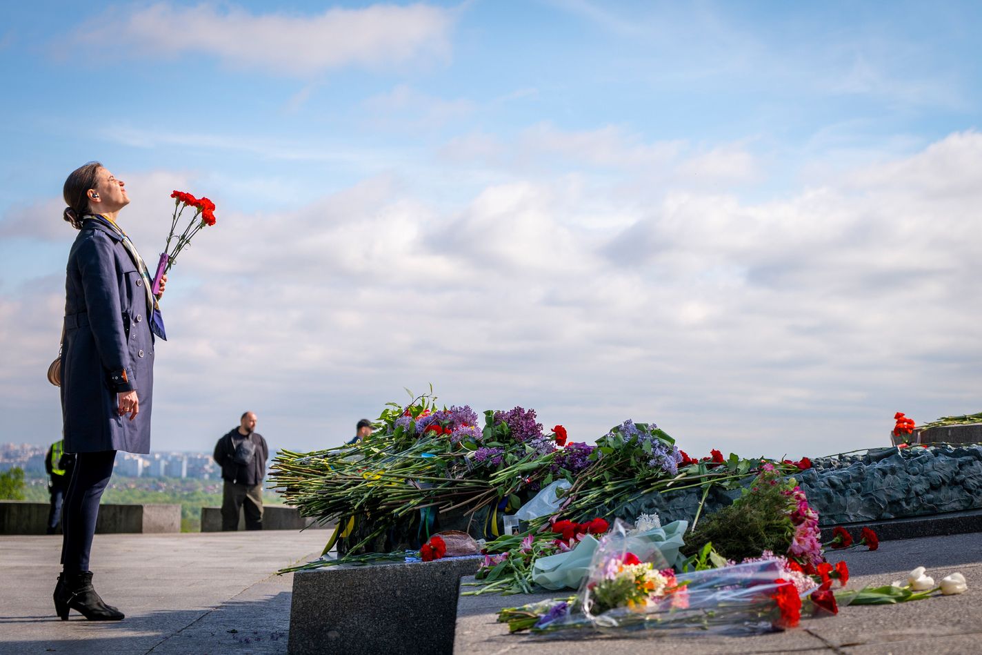 A woman holds flowers near the Eternal Flame in the Park of Eternal Glory.