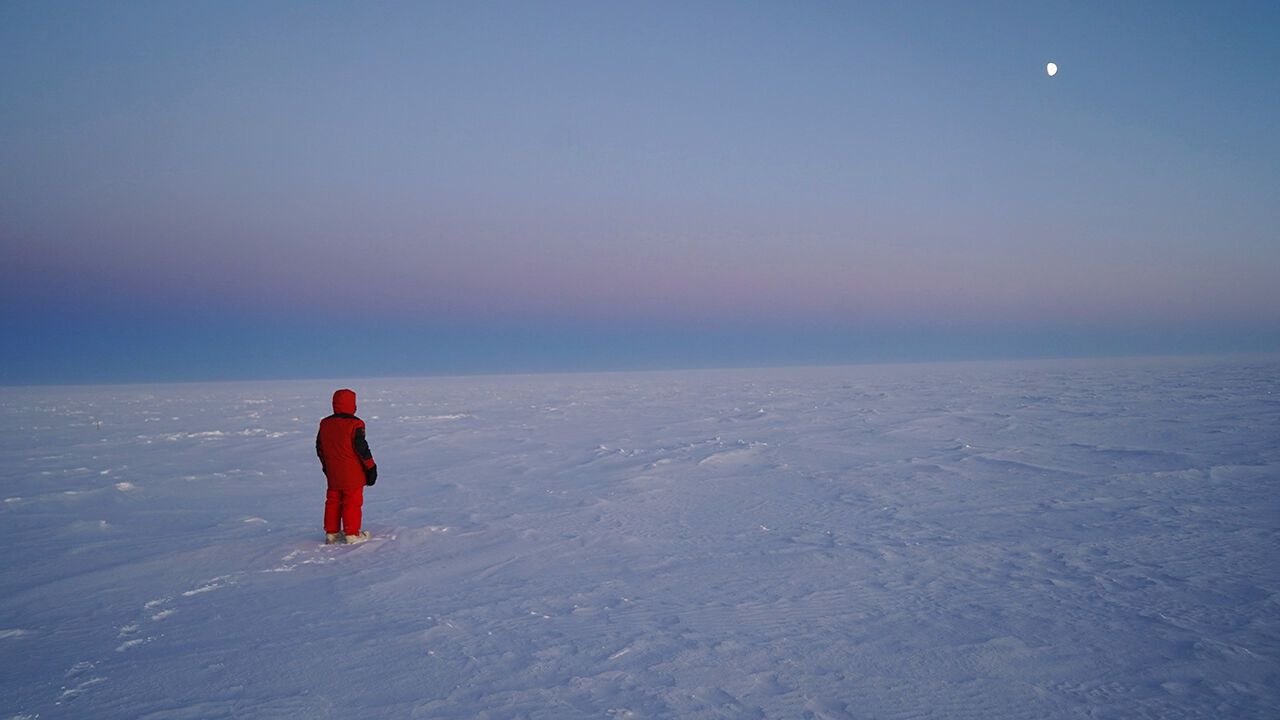 Concordia research station, person gazing at the Moon and the vast expanse of Antarctica.