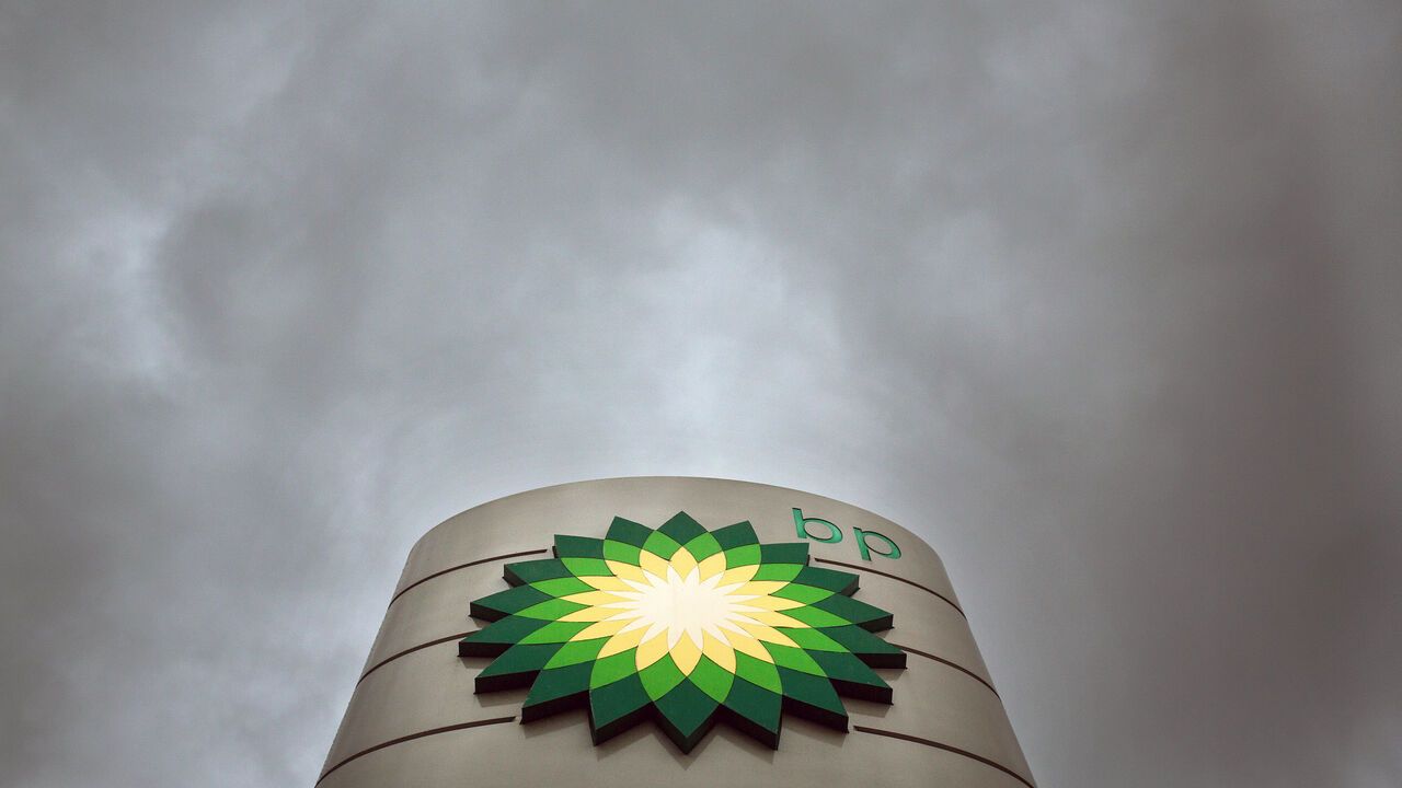 BP Plc logo sits on a totem sign outside a gas station under a cloudy sky.