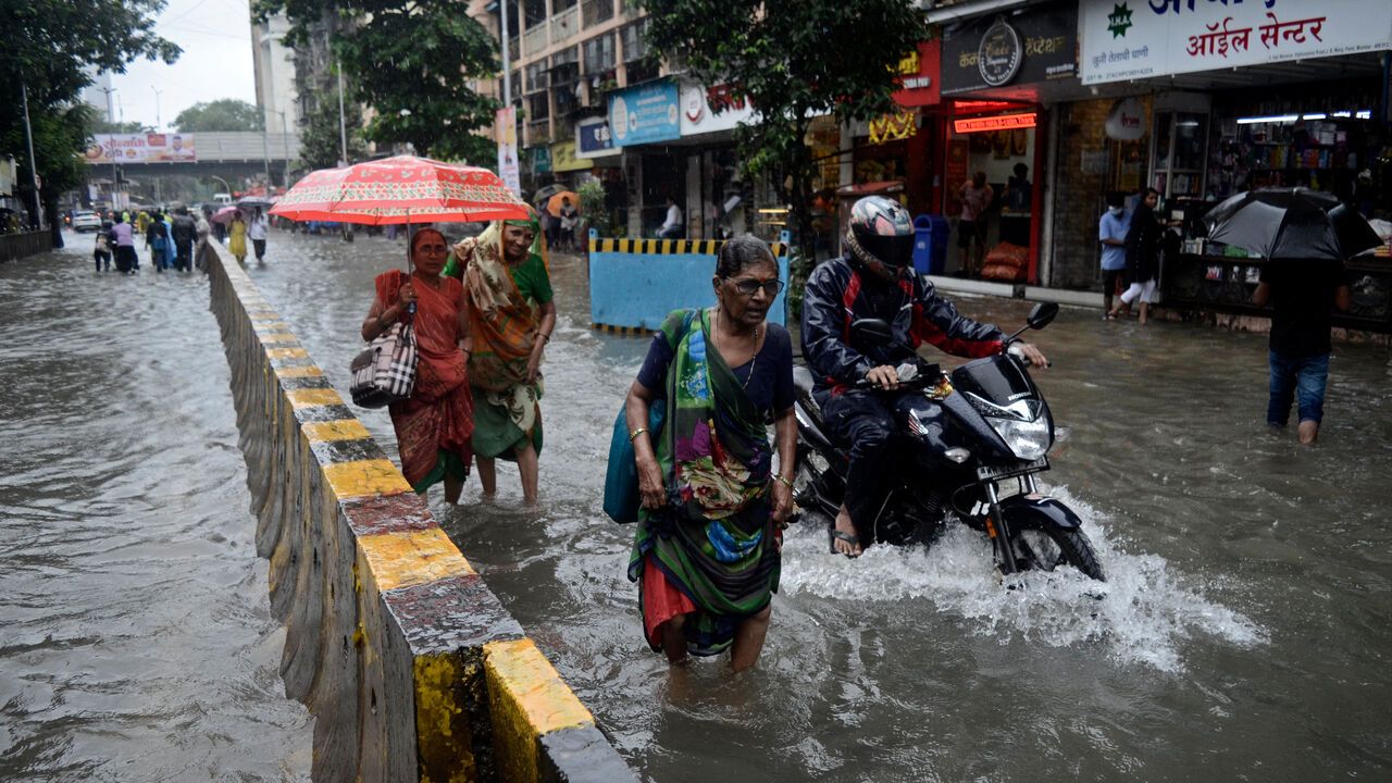 Floodwaters submerge a street as vehicles and pedestrians navigate after heavy rains in Mumbai, India.