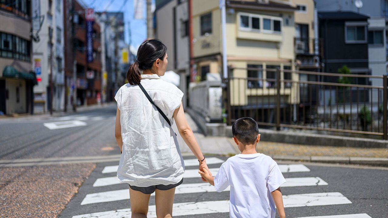A woman is crossing the road with her child in Japan