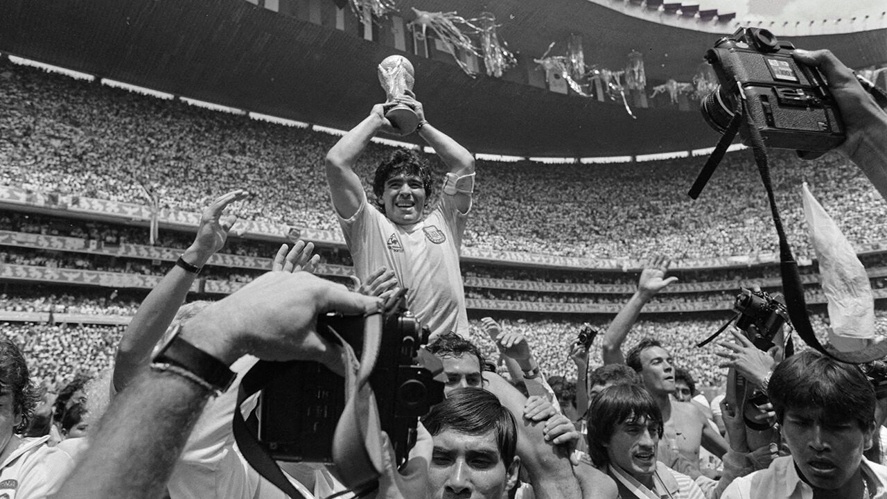 Argentina's Diego Maradona celebrates holding the World Cup trophy aloft as he is carried off the field after Argentina won the World Cup Final