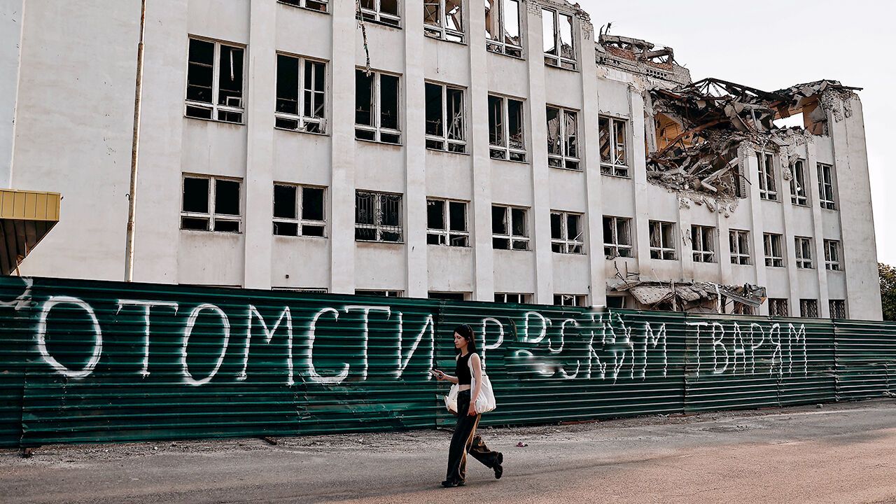 A woman walks past a building partially destroyed by Russian shelling in Kramatorsk, Ukraine