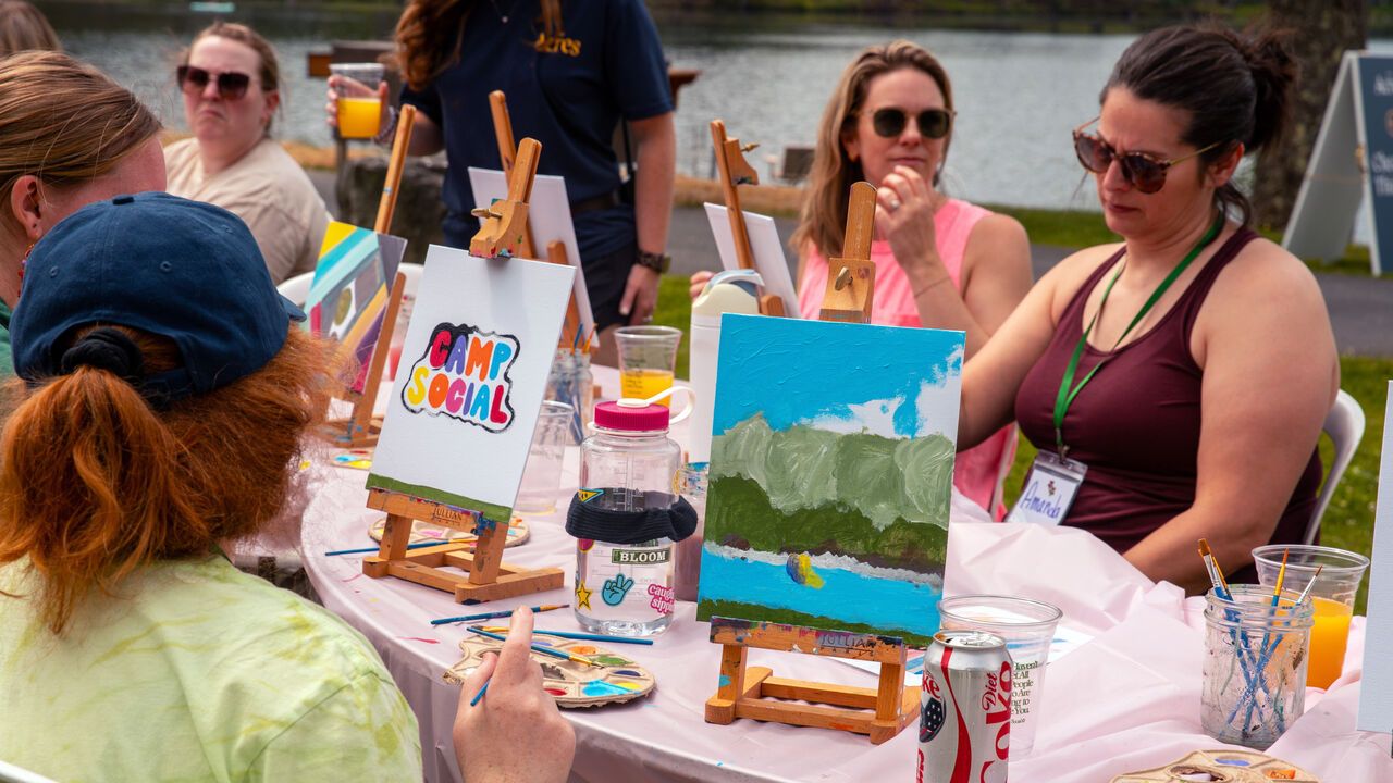 People take part in a painting class while attending Camp Social