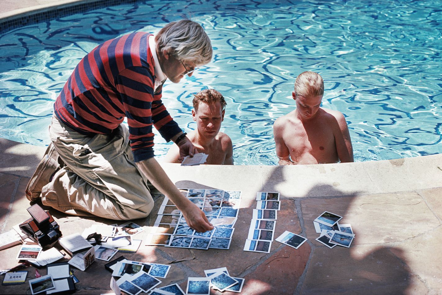 David Hockney, poolside in Los Angeles, with polaroids of David Stoltz & Ian Falconer, circa 1978