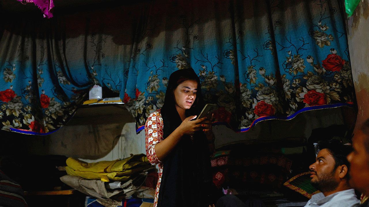 A teenage girl types on a mobile phone as her parents look at her at their residence in Loni town in the northern state of Uttar Pradesh, India, September 18, 2024.