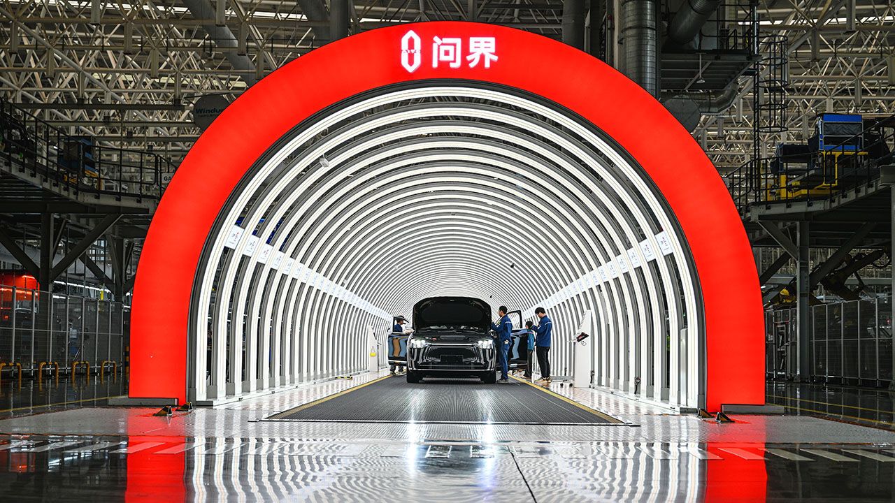 Employees check new energy vehicles before they roll off the production line at Seres Super Factory in Chongqing, China