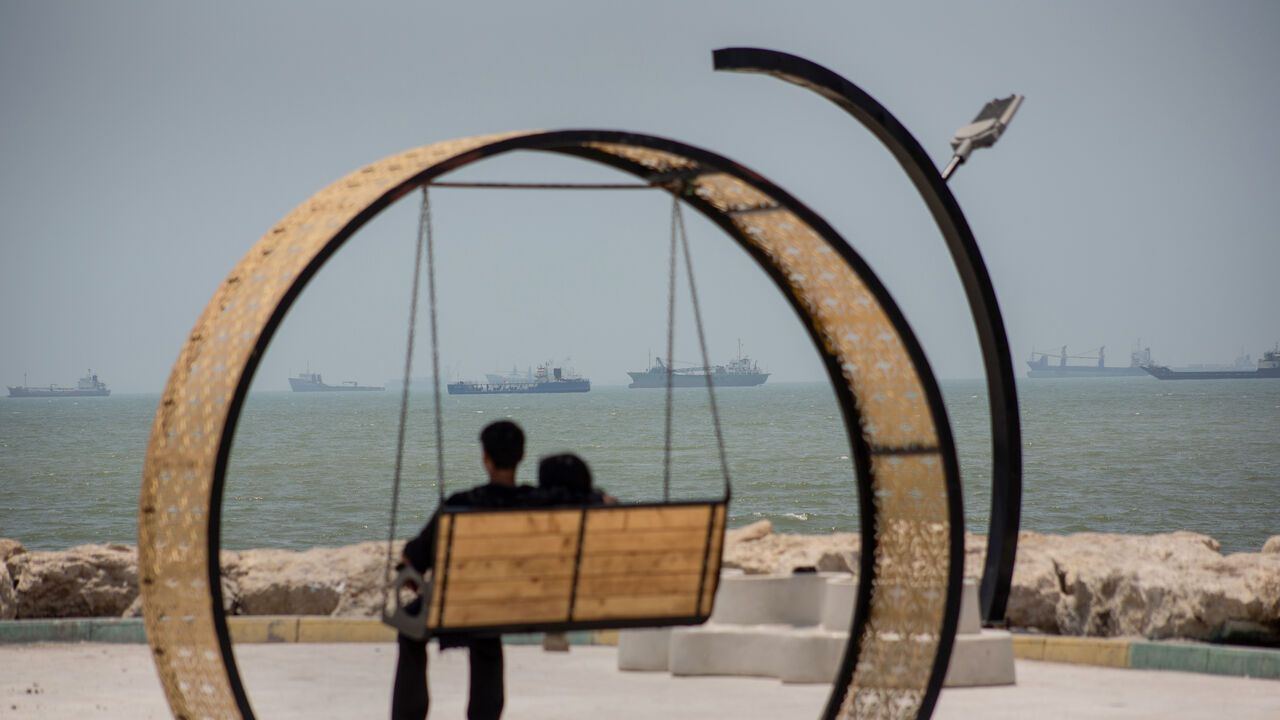 Large commercial vessels and a small boat navigate the waters off the southern port city of Bandar Abbas, Iran.