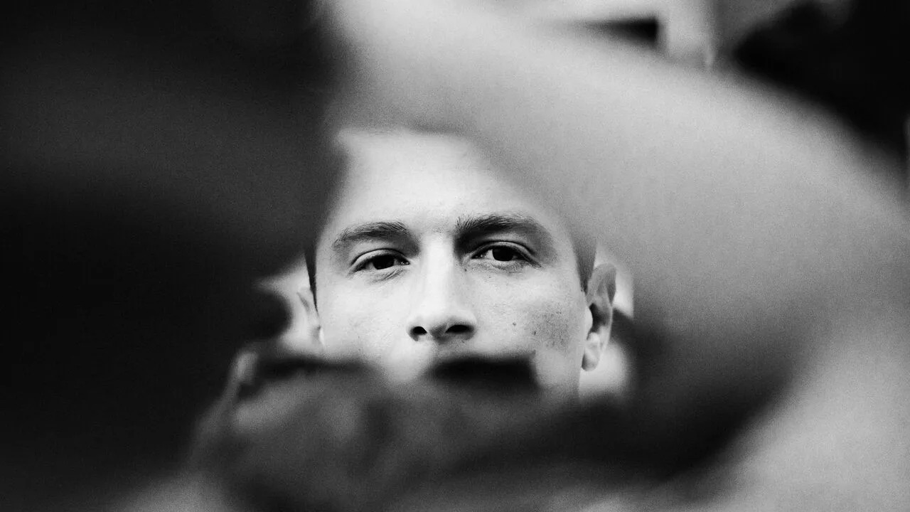 Black and white photo of Jordan Bardella looking to camera.