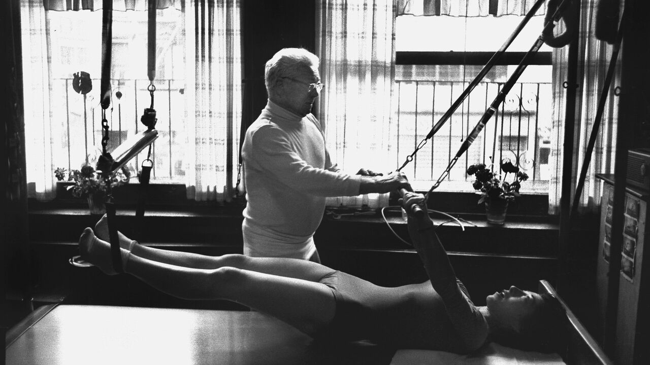 Joe Pilates, Inventor, physical fitness guru and founder of the Pilates exercise method instructs a client.