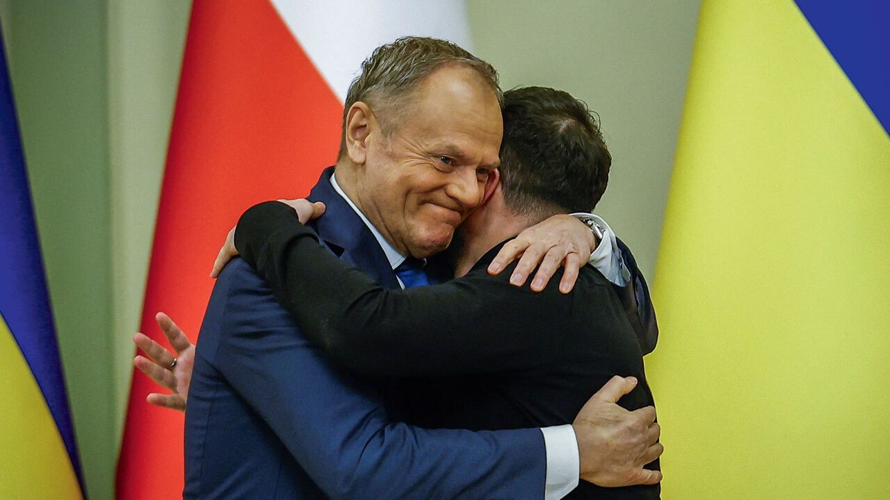 Polish Prime Minister Donald Tusk and Ukrainian President Volodymyr Zelenskiy embrace each other as they attend a joint press conference.