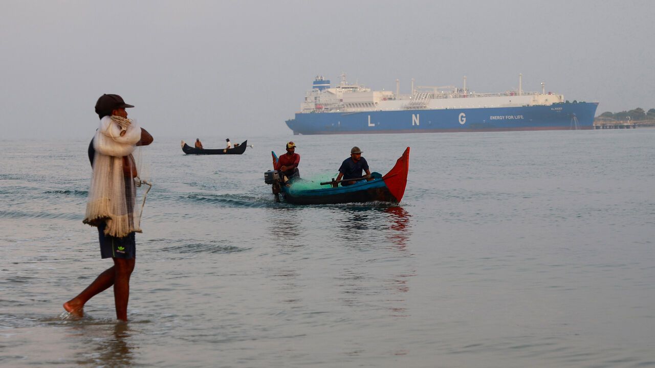 Fishermen in their traditional boats pass through the Arabian Sea with the LNG tanker Al Reef in the background in Kochi, India.
