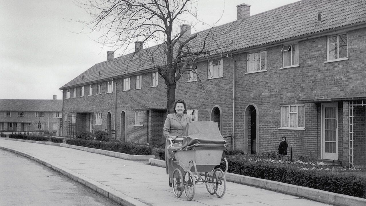 A woman pushes a pram past a row of council houses in the Adeyfield district of Hemel Hempstead, Hertfordshire.