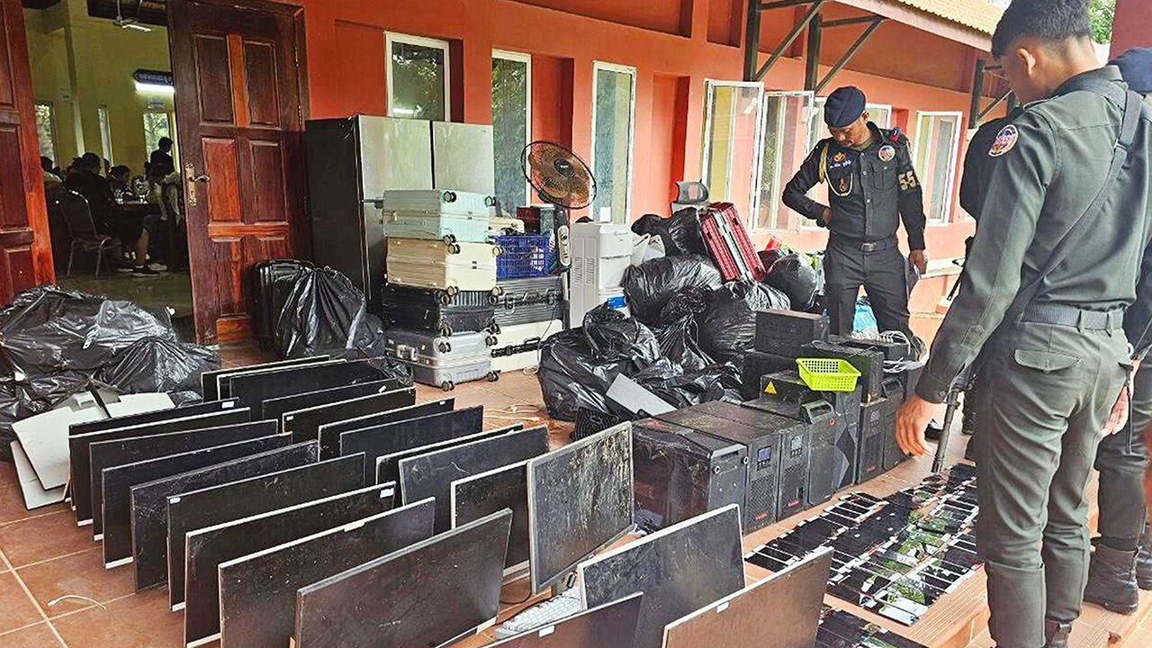 Military police looking at computers, smartphones and other equipment seized during a raid on a scam centre in Kandal province, July 2025.