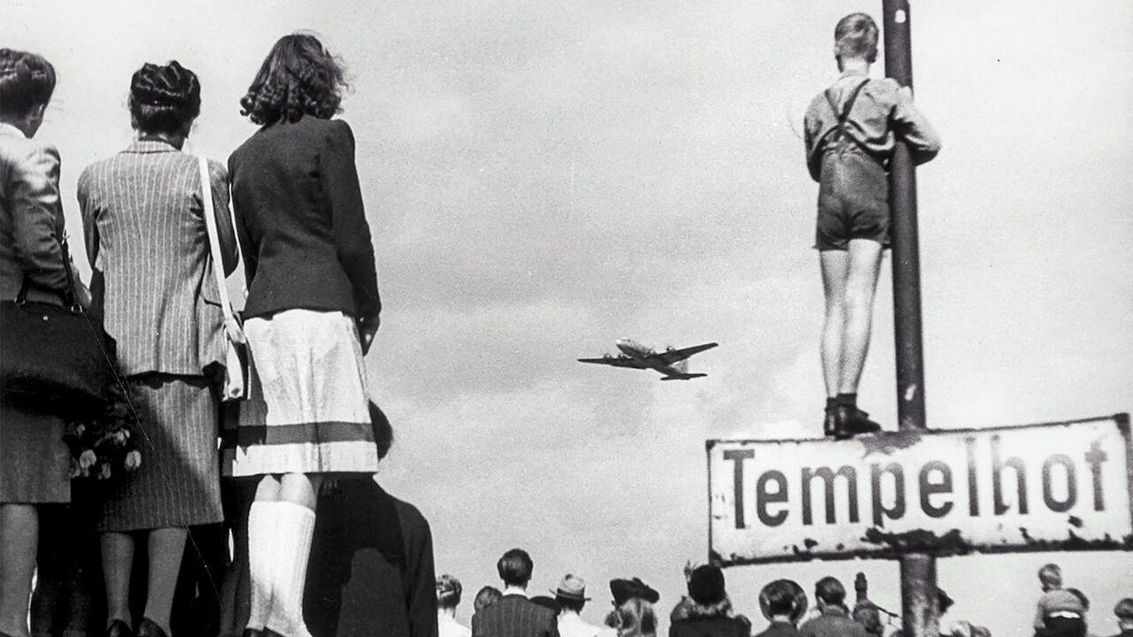 Crowds watch an American aircraft bringing supplies at Tempelhof Airport in 1948