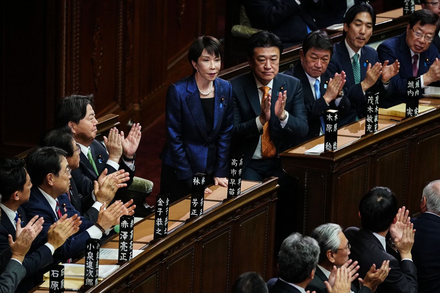 Sanae Takaichi (C) stands after winning Japan's prime ministerial designation vote in the House of Representatives in Tokyo, Japan, Feb. 18, 2026.