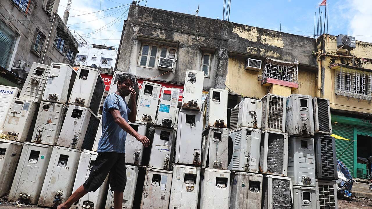 A worker walks past air conditioning units in Kolkata, India