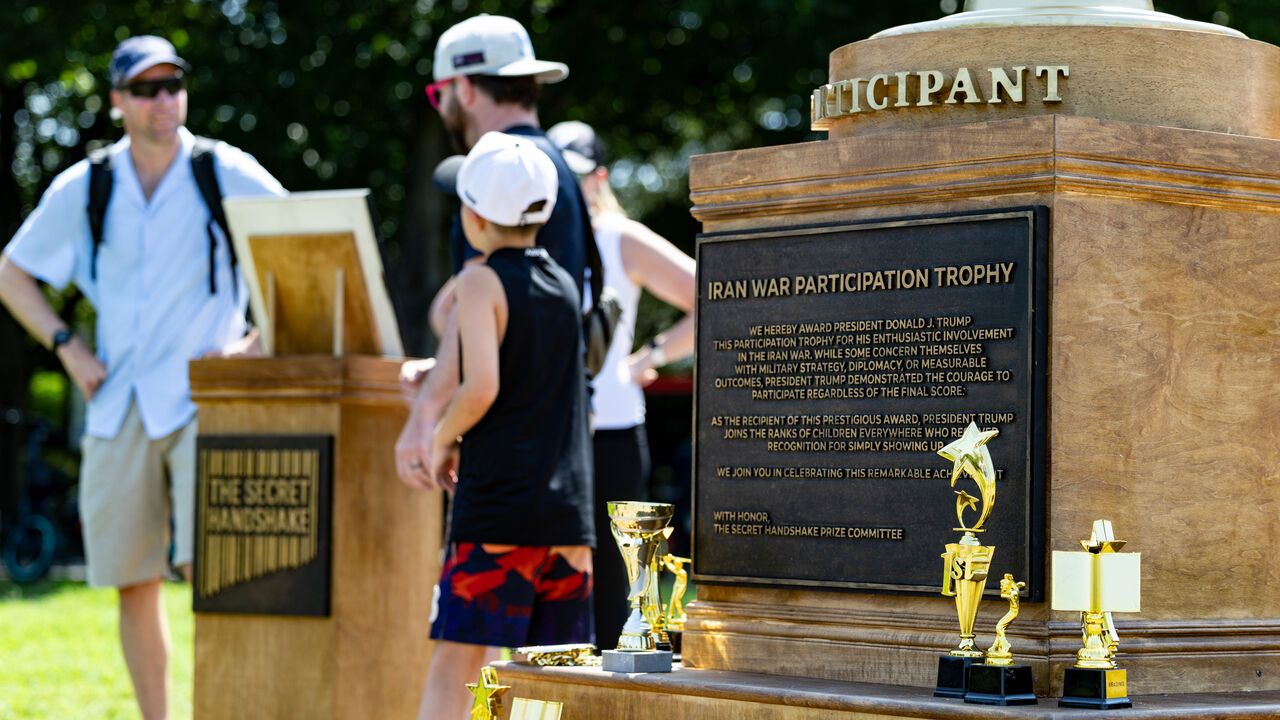 People standing next to an Iran War Participation Trophy dedicated to President Donald Trump appears next to the MLK Jr. Memorial Bookstore in Washington, DC, USA.