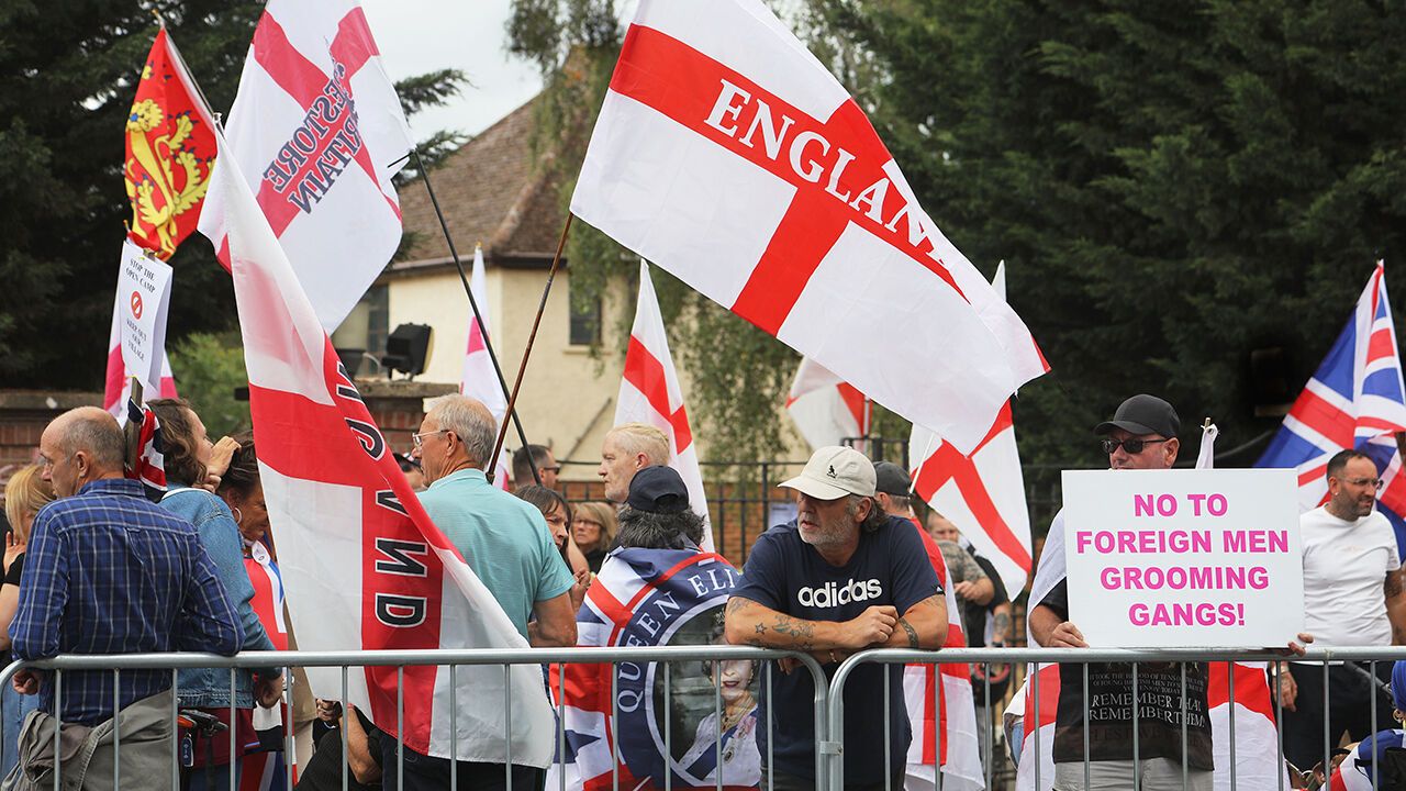 A protester holds a sign saying "No foreign grooming gangs" at a planned protest site for an asylum-seeker centre in Thetford, UK, on July 19th 2026