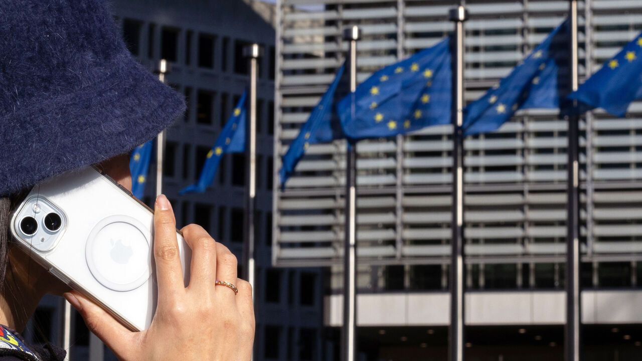 A woman talks through an iPhone at the Berlaymont building, headquarters of the European Commission, in Brussels.