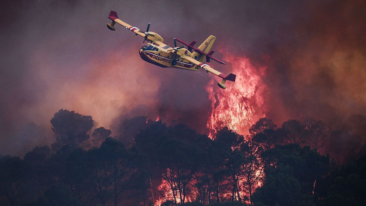 A French Civil Security Canadair CL-415 aircraft flies past flames burning a forest outside Cotignac, France on July 23rd 2026