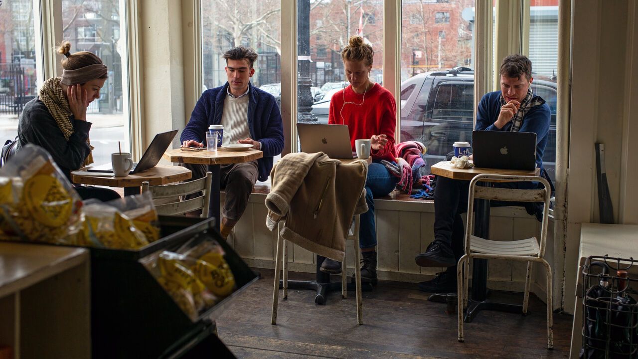 Patrons at a cafe use their laptop computers.