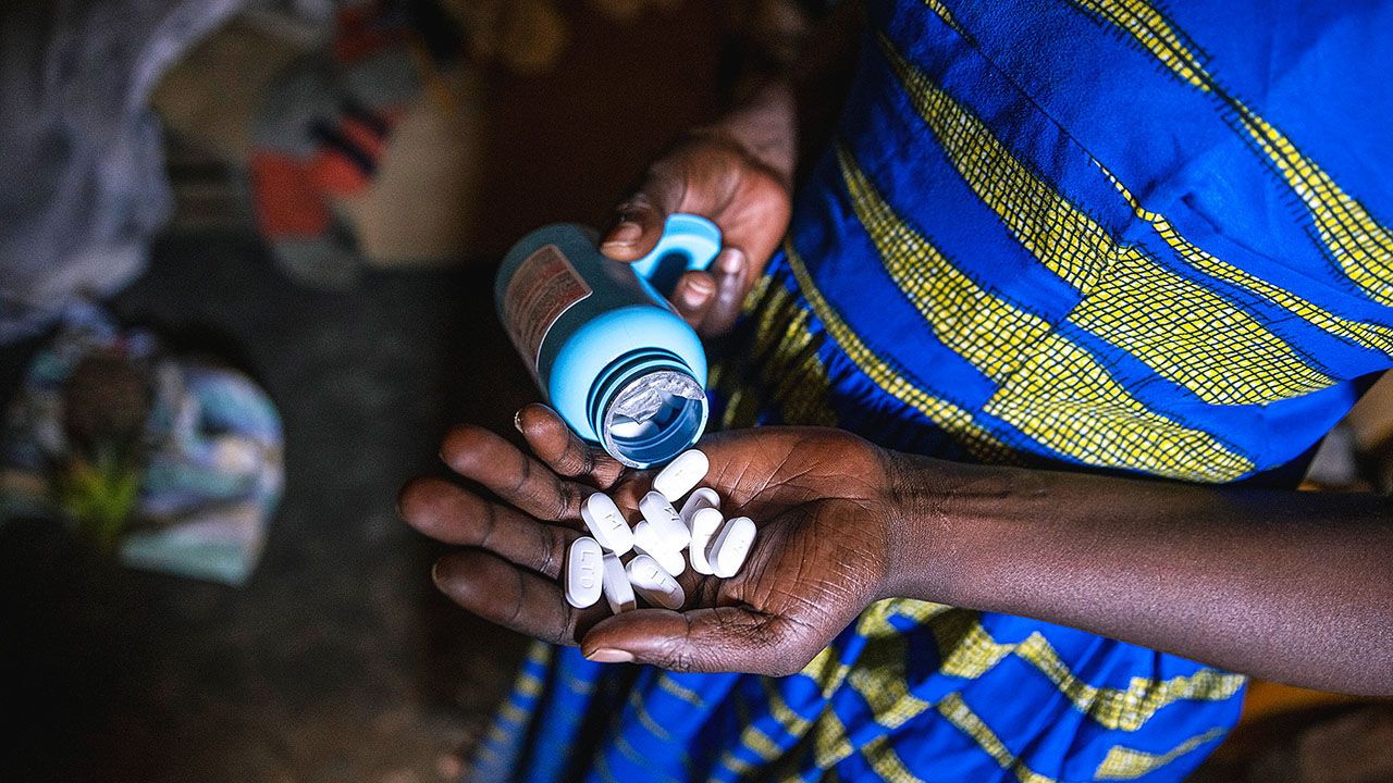 A mother holds out a handful of ARV treatment belonging to her children.