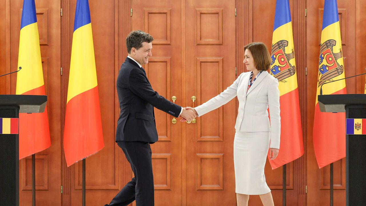 Moldova's President Maia Sandu (R) and Romania's President Nicusor Dan (L) shake hands during a joint press conference.