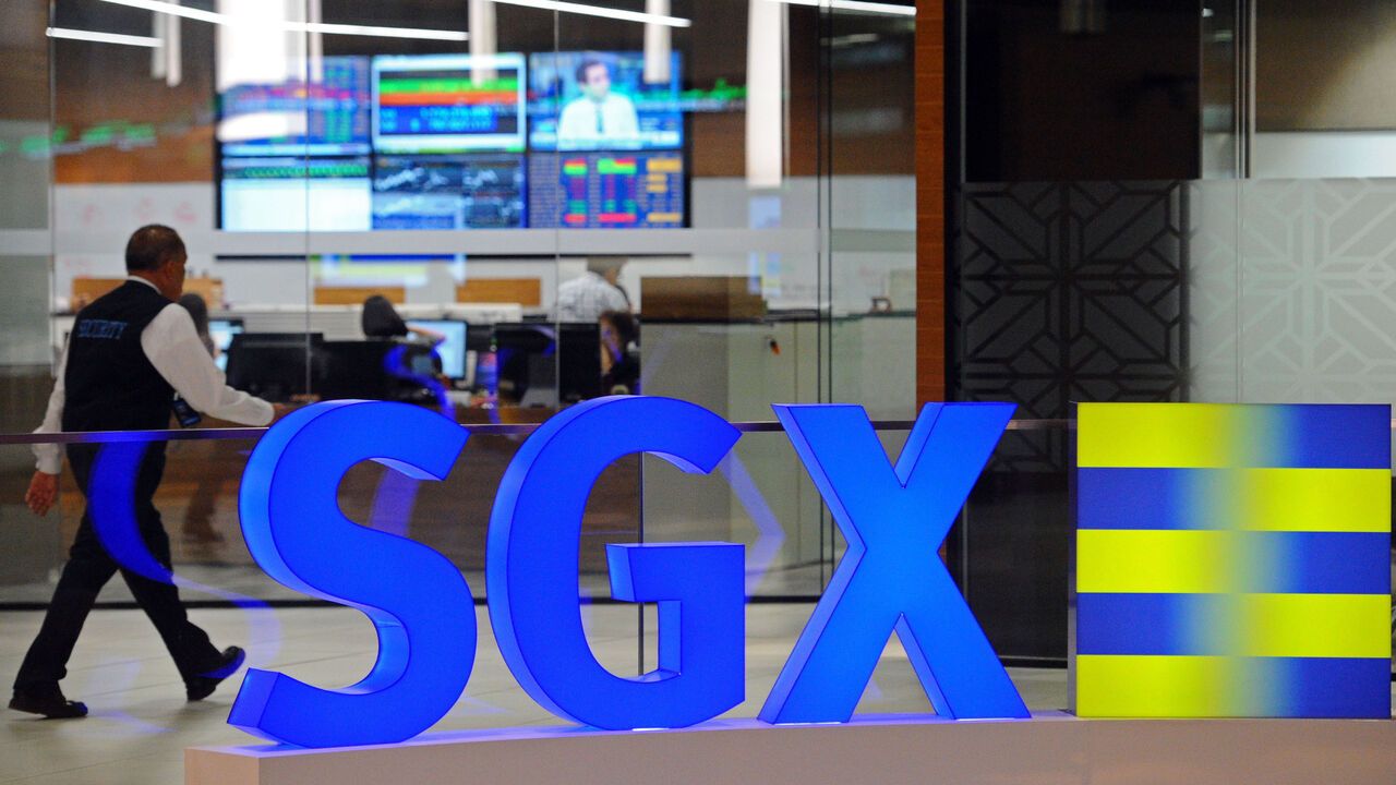 A staff member walks past blue and yellow SGX office signage in Singapore Exchange (SGX).