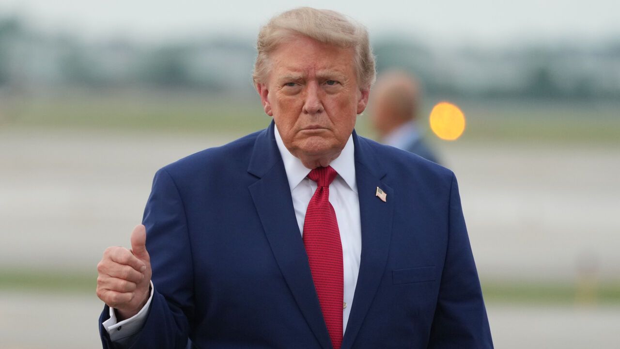 President Donald Trump walks from Marine One to board Air Force One, gesturing a thumbs up.