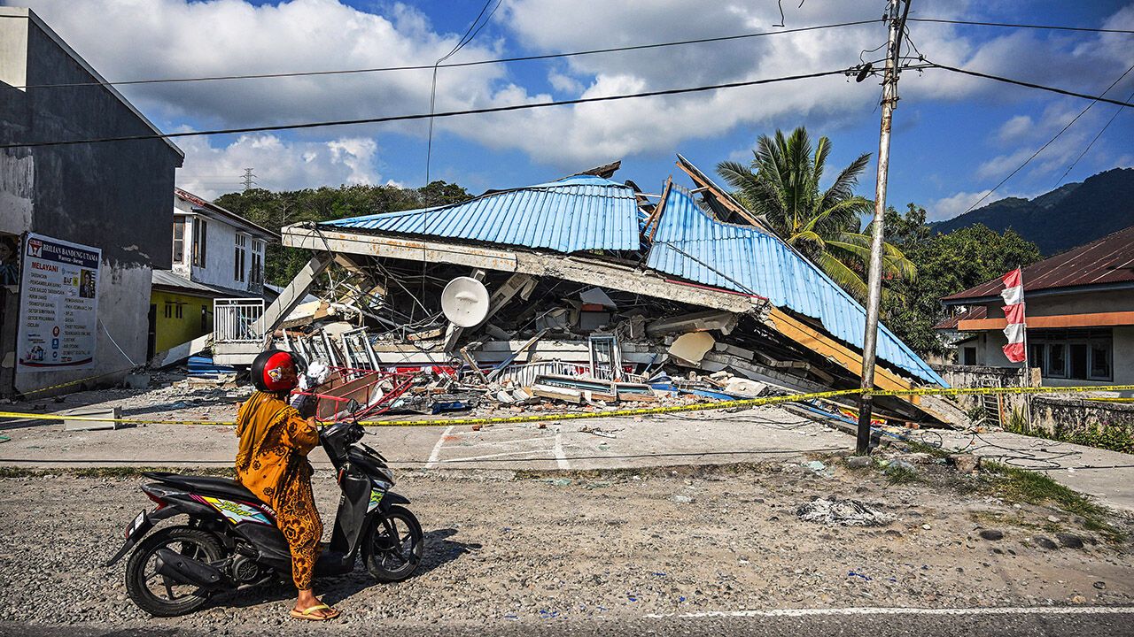 A motorbike stops next to a collapsed building following an earthquake in Indonesia.