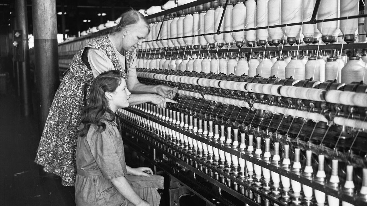 Mill worker Mrs E Cocker instructs Miss E Crossdale in the piecing up on the ring frame at the Talbot Spinning and Weaving Co Ltd, in Chorley, Lancashire, circa 1950