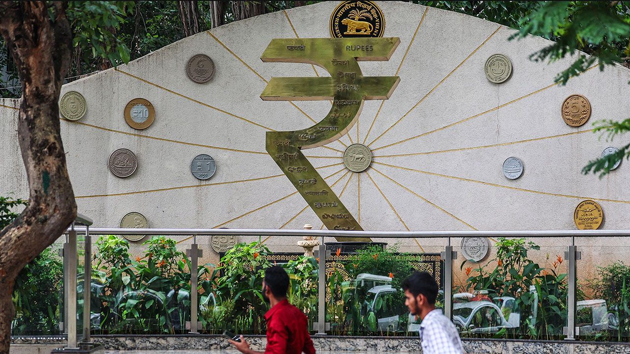 People walk past the Indian rupee symbol near the Reserve Bank of India (RBI) headquarters in Mumbai, India.