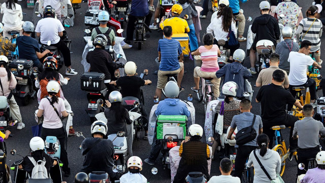 People on scooters and bicycles queue on a crossroad in Beijing.