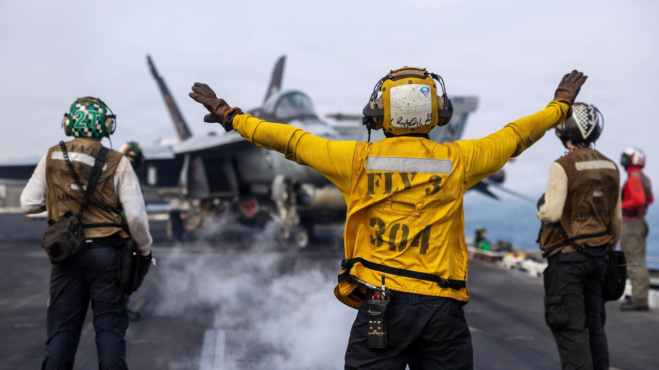 A U.S. Sailor directs an F/A-18F Super Hornet, assigned to Strike Fighter Squadron (VFA) 41, on the flight deck of Nimitz-class aircraft carrier USS Abraham Lincoln.